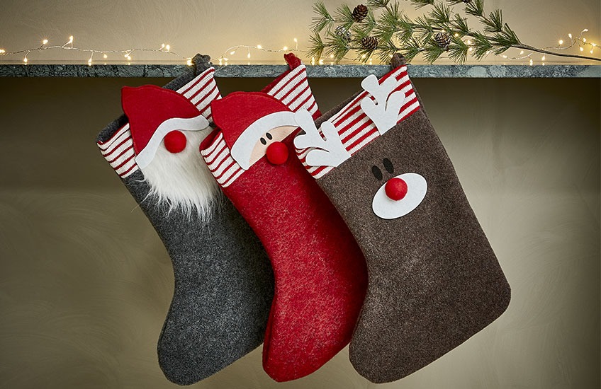 Calze di Natale appese sullo scaffale con motivo di Babbo Natale, elfo e renna