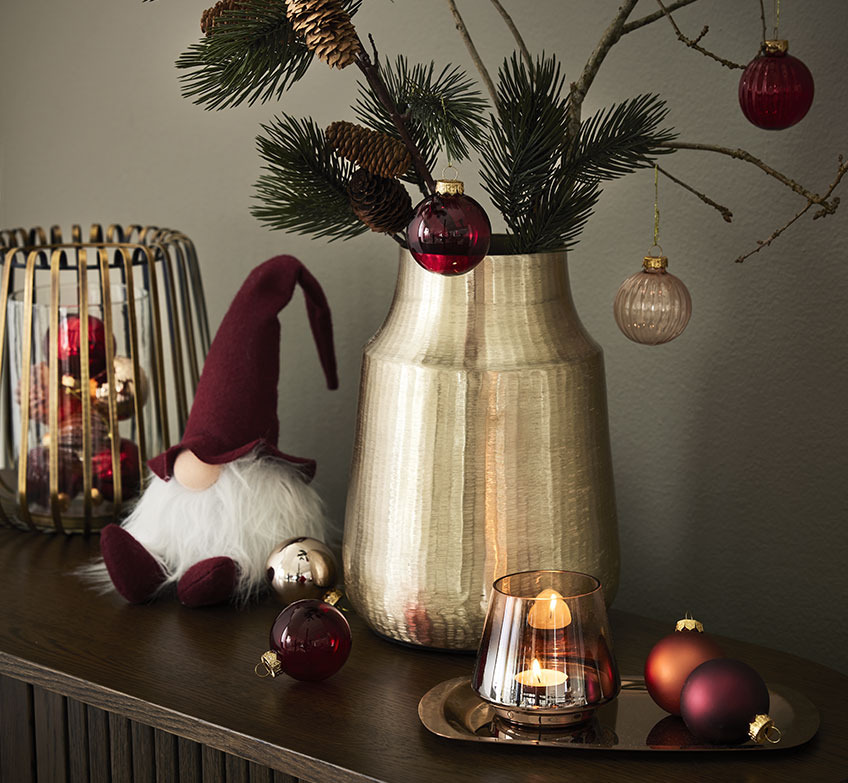 Portacandele dorato, elfi natalizi e vaso dorato con rami di abete e decorazioni natalizie